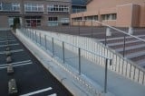 小学校に新設されたスロープの手すり。奥の階段手すりは既存のものです。既設、新設違和感なく施工いたします。